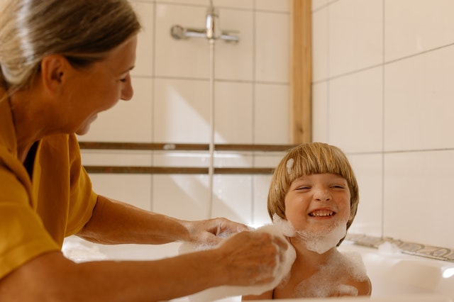 A woman helping her son take a bath