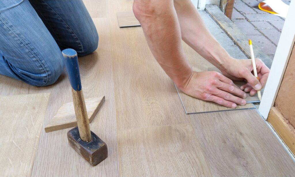 A man doing some measuring on the floor, obviously trying to replace the flooring properly.