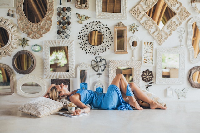 A woman lying on the floor near the wall full of mirrors showing small space decorating ideas for apartments.