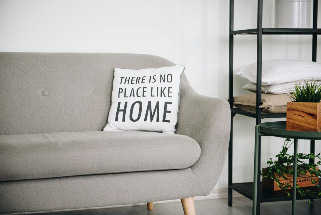 A comfy-looking couch and a pillow that says, ‘There is no place like home.’